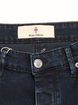 Close-up of BGvinci Black OD Jeans in blue black denim, highlighting the Blue de Gênes fabric label with red shield logo on the waistband and a branded metal button also featuring the Blue de Gênes name and logo.