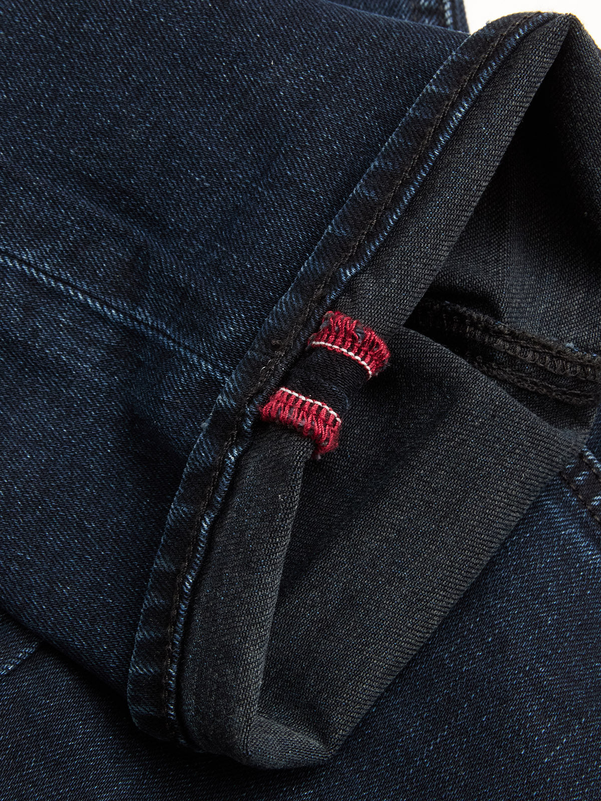 A close-up of the cuff on BGvinci Black OD Jeans by Blue de Gênes in blue black denim, showing a visible red and white selvedge edge and contrasting stitching.