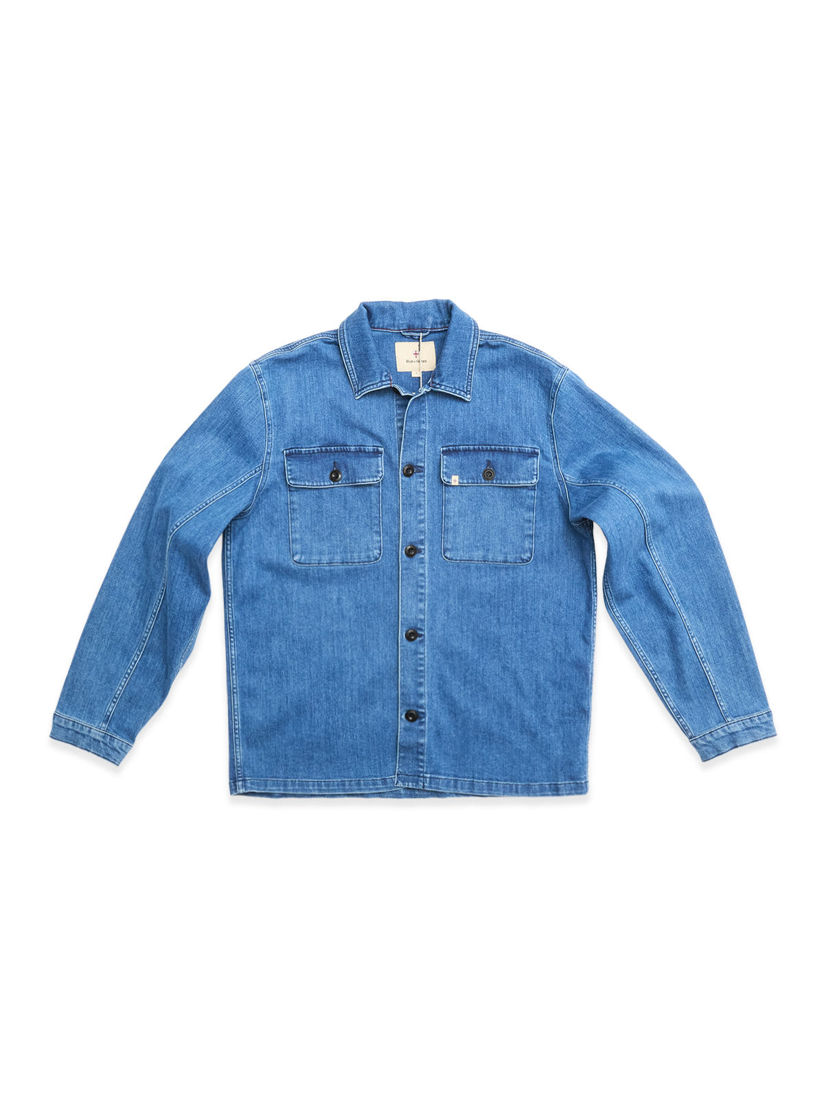 The BGpontus Denim Overshirt - Used by Blue de Gênes is a light blue, relaxed fit cotton blend overshirt with long sleeves, a collar, black front buttons, and two buttoned chest pockets. Shown laid flat on a white background.