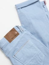 The BGpaulo Pavia Pant in Blue Fog by Blue de Gênes is crafted from cotton stretch fabric, neatly folded with a brown leather logo patch above the back pocket, displayed on a white background.
