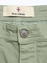 Close-up of BGpaulo Pavia Pant in Shadow Green cotton stretch, featuring a metal button and beige label above the waistband. Both display the Blue de Gênes name and shield logo.