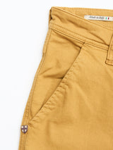 Close-up of BGpaulo Pavia Pant - Sunflower by Blue de Gênes: mustard yellow chino with front pocket, visible stitching, shield emblem, and Italian flag waistband label. Made in Italy from cotton stretch fabric with vintage military inspiration.