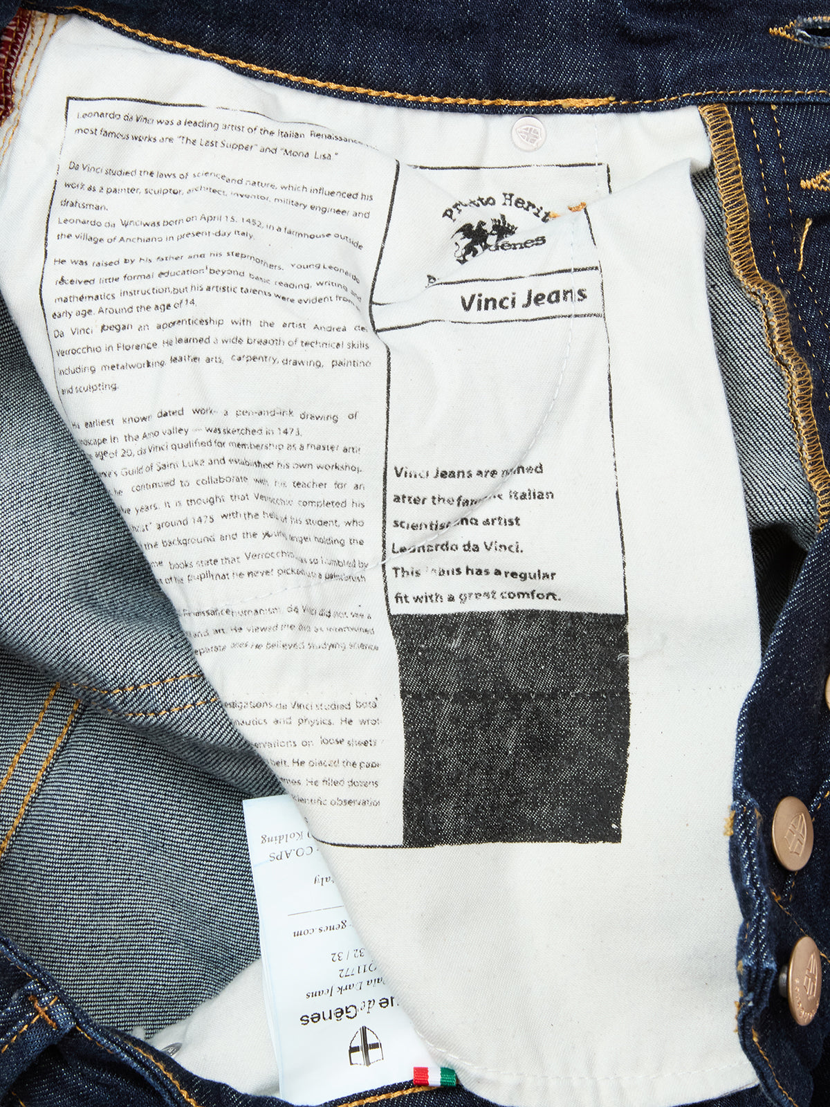 The inside of Blue de Gênes Vinci Pala Dark V2 Jeans in dark blue denim, made in Italy, features a white pocket lining printed with Leonardo da Vinci and brand text, plus blue comfort stretch denim and brown metal buttons.