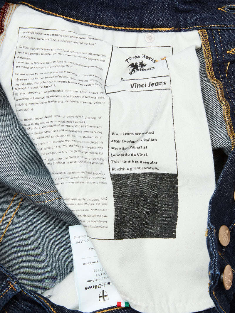 The inside of Blue de Gênes Vinci Pala Dark V2 Jeans in dark blue denim, made in Italy, features a white pocket lining printed with Leonardo da Vinci and brand text, plus blue comfort stretch denim and brown metal buttons.
