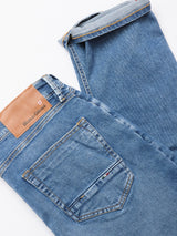 The Vinci Pala Used V2 Jeans by Blue de Gênes are regular fit, denim blue jeans in comfort stretch fabric, featuring a brown leather brand patch. Shown laid flat on a white background, highlighting the back pocket and waistband.