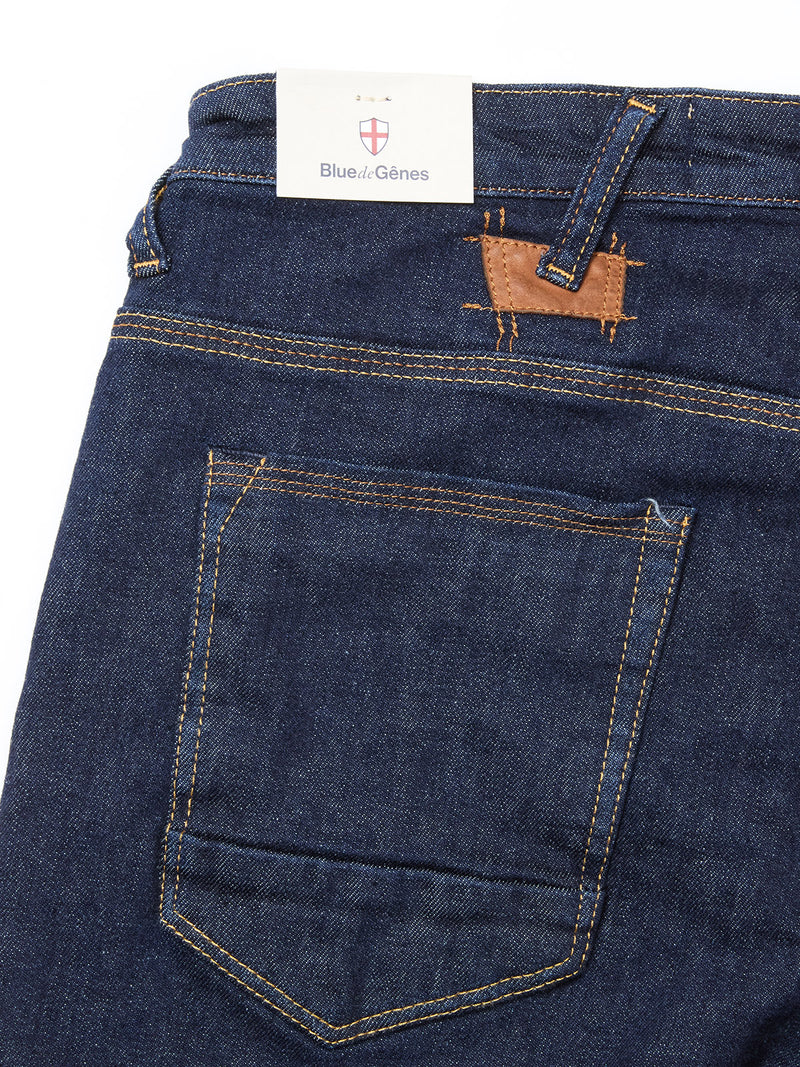 A close-up of the back pocket and waistband of Blue de Gênes Repi Dai V Dark V2 Jeans in dark blue denim, featuring yellow stitching, a Blue de Gênes tag in the waistband, and a small brown leather patch above the pocket.