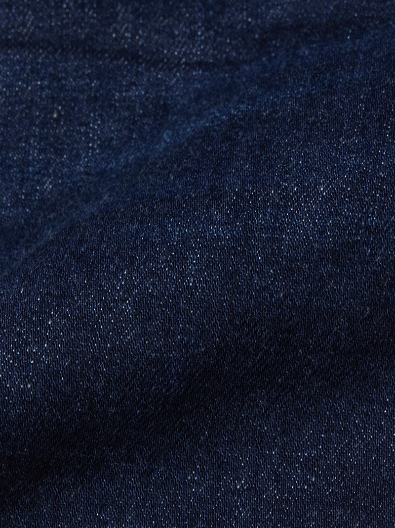 Close-up of durable dark blue denim fabric from Blue de Gênes Repi Dai V Dark V2 Jeans, highlighting the slim-fit texture, visible weave, gentle fold, and subtle color variations.