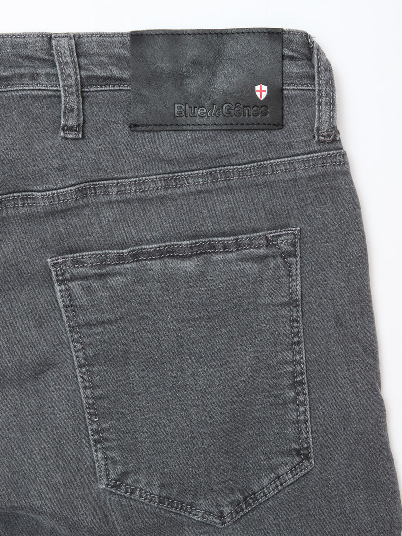Close-up of the back of Blue de Gênes Repi Giulio Light V2 Jeans in grey denim, featuring comfort stretch fabric, a single rear pocket, and a black leather patch with brand logo plus a red and white shield above the waistband.