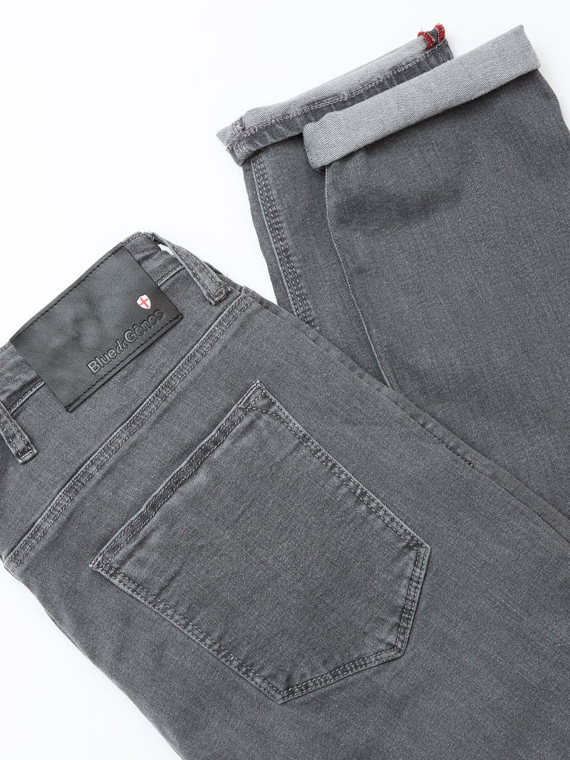 A pair of folded Repi Giulio Light V2 Jeans in grey denim with a visible back pocket and a black label on the waistband displaying the Blue de Gênes brand name.