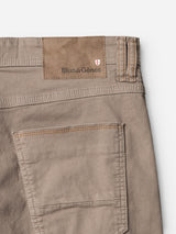 Close-up of the BGpaulo Pavia 1 V2 Chino - Fungi by Blue de Gênes in beige cotton stretch, showing the stitched back pocket and a brown leather patch with Blue de Gênes branding and a red and white shield logo.
