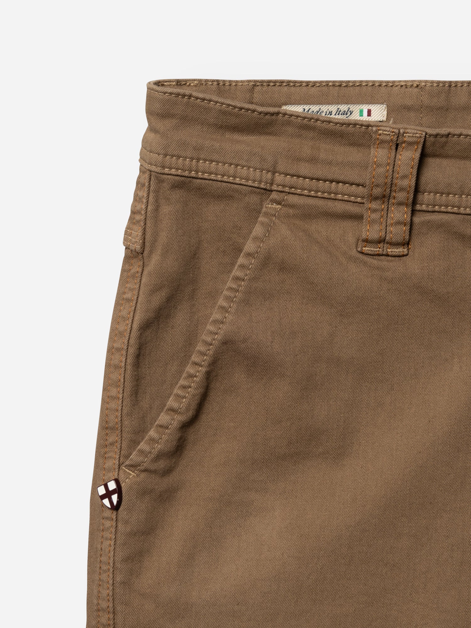Close-up of Blue de Gênes BGpaulo Pavia 1 V2 Chino - Fudge showing waistband, front pocket, belt loop, Made in Italy label with Italian flag, and stitched emblem near the pocket on these cotton stretch chinos.