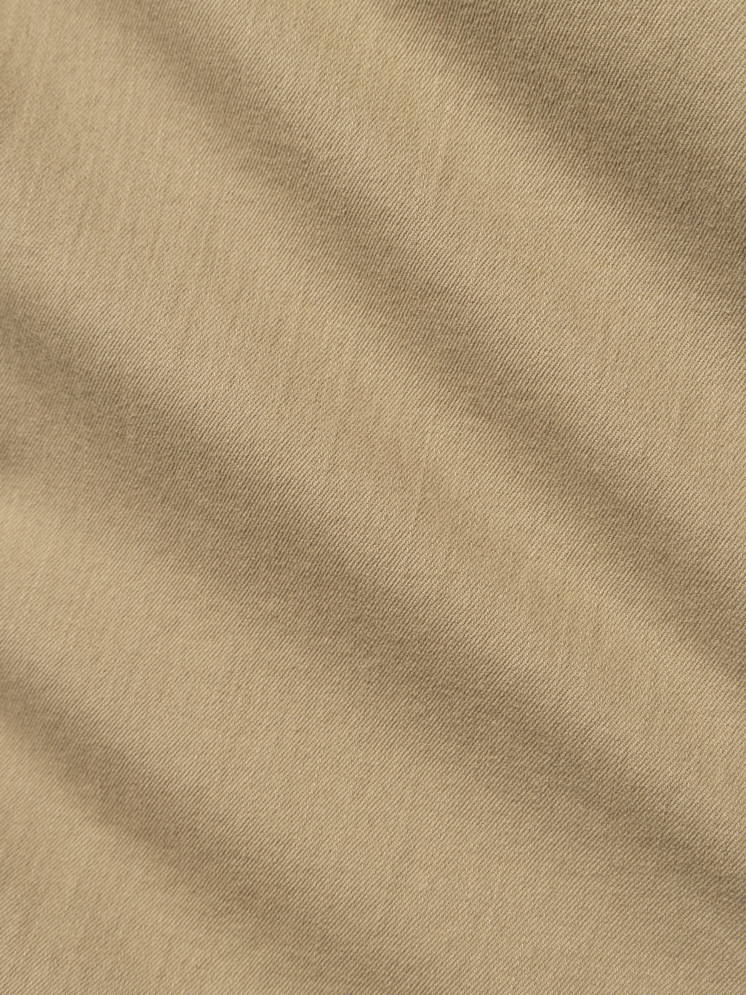 Close-up of Blue de Gênes BGpaulo Pavia 1 V2 Chino - Khaki, featuring beige cotton stretch fabric with a soft woven texture, diagonal creases, matte finish, and subtle color variations inspired by vintage military pants.