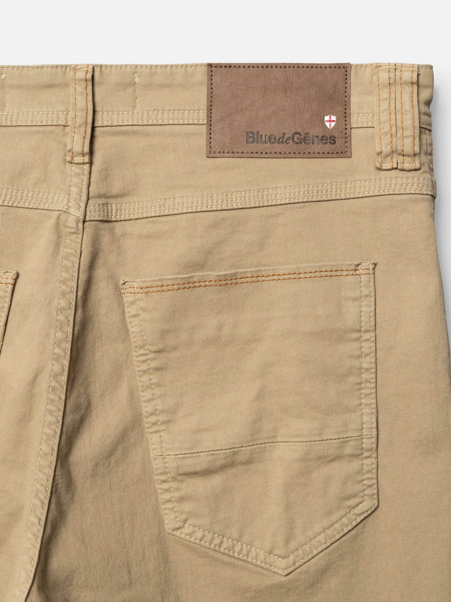 Close-up of the BGpaulo Pavia 1 V2 Chino - Khaki by Blue de Gênes, crafted from cotton stretch fabric, featuring a single back pocket and a brown leather patch on the waistband with brand name and a small red and white shield logo.