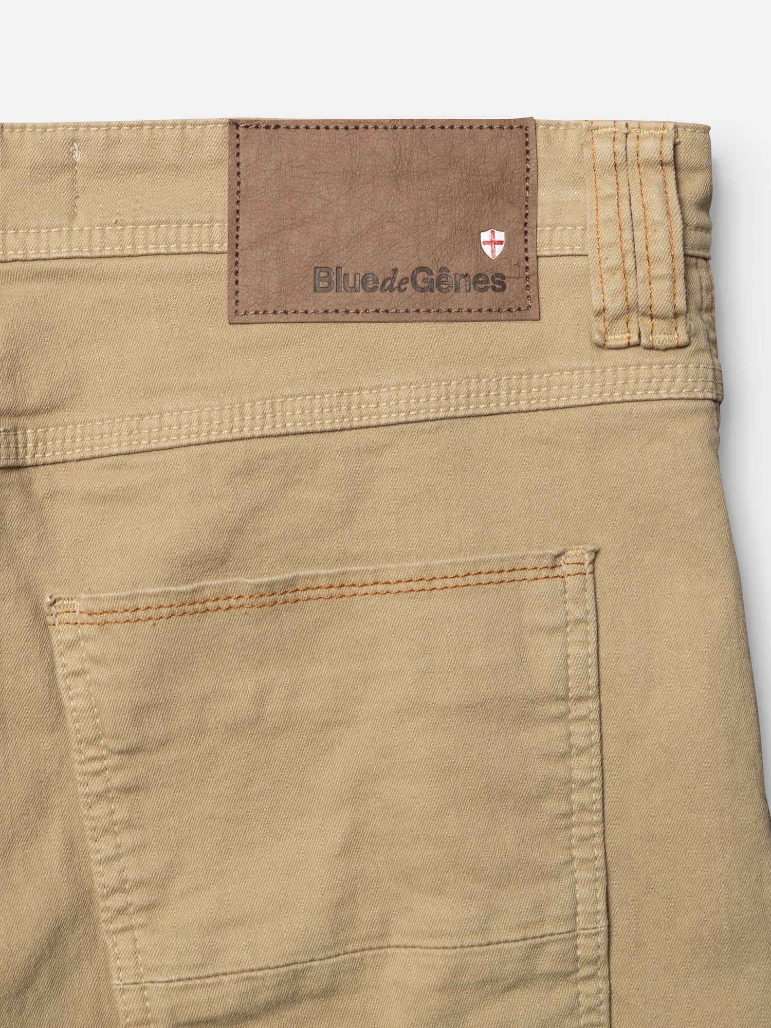 Close-up of the BGpaulo Pavia 1 V2 Chino in khaki by Blue de Gênes, showing a stitched back pocket, a brown leather patch with the brand’s name and shield emblem, crafted from stretch cotton fabric.