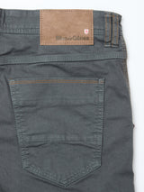Close-up of the back pocket and waistband of Blue de Gênes Paulo Pavia 1 V2 Chino - Charcoal, made from stretch cotton with brown stitching, a brown leather Blue de Gênes patch, and a small red and white shield logo above the pocket.