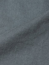 Close-up of Blue de Gênes Paulo Pavia 1 V2 Chino in charcoal shows its blue-gray denim fabric with a diagonal weave and subtle texture variations, reminiscent of vintage military pants, featuring a visible diagonal seam.