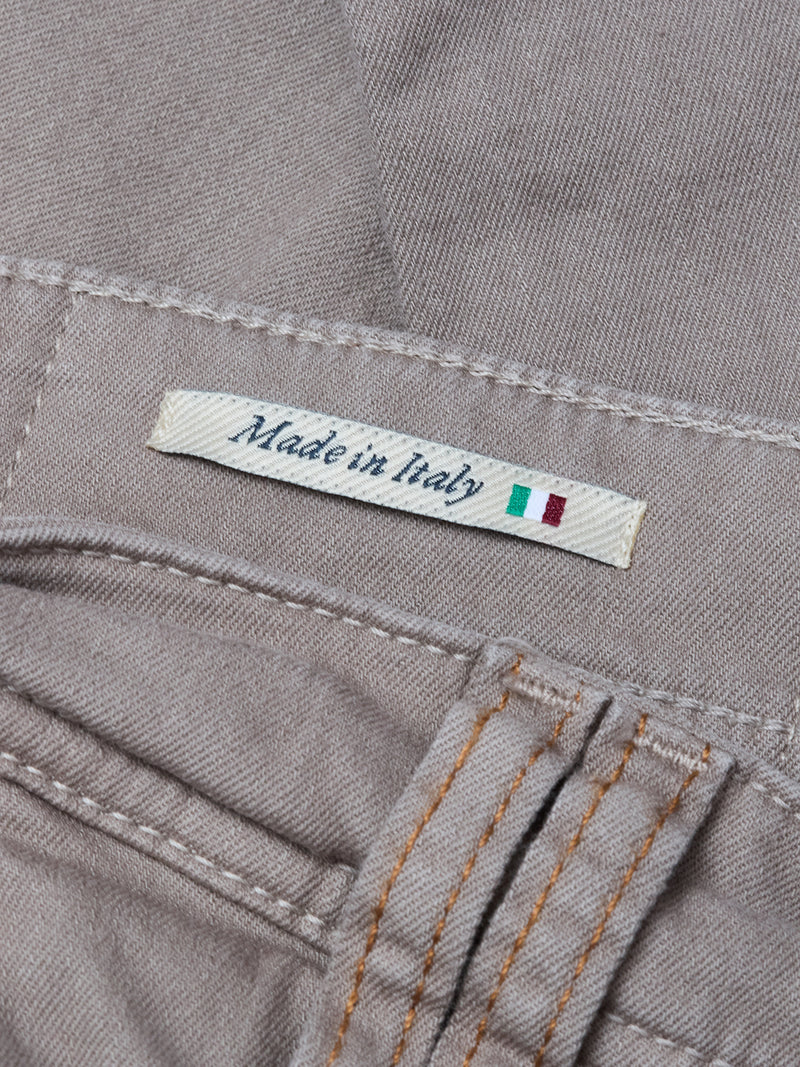 A close-up of the Blue de Gênes Paulo Pavia 1 V2 Chino - Fungi label sewn onto light brown fabric, marked Made in Italy with a small Italian flag and orange stitching on these vintage-inspired military pants.