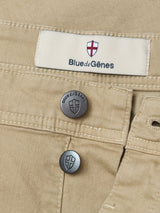 Close-up of Khaki Paulo Pavia 1 V2 Chino trousers by Blue de Gênes, featuring two shield-logo metal buttons and a fabric label with the brand’s red and white shield emblem, crafted from cotton stretch inspired by vintage military pants.
