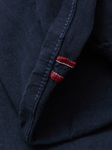 Close-up of Blue de Gênes Paulo Pavia 1 V2 Chino in Midnight Blue: folded cotton stretch fabric with visible stitching and a red-and-white striped accent near the seam, evoking vintage military pant details.