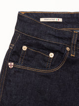 Close-up of Blue de Gênes Recco F V2 Jeans - Rinse Wash in dark blue denim with yellow stitching, metal rivets, a small pocket, and an Italian flag “Made in Italy” label inside the waistband; a crest adorns the front pocket.
