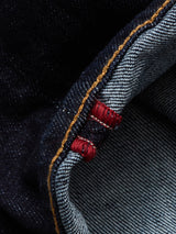 Close-up of Blue de Gênes Recco F V2 Jeans - Rinse Wash, highlighting the raw denim selvedge with a white and blue striped interior, red stitch, and contrasting orange stitching on the dark blue exterior.