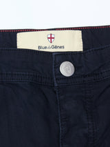 Close-up of the waistband of BGpaulo Teo Pant - Dark Navy by Blue de Gênes, featuring a label with red cross shield, branded metal button, and stitching details inspired by vintage military style.