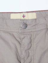 Close-up of the waistband and button of Blue de Gênes BGpaulo Teo Pant in flint gray, showing a metal embossed logo button and a small England flag patch sewn inside the waistband.