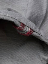 Close-up of the BGpaulo Teo Pant in Flint gray by Blue de Gênes, featuring textured cotton, a folded seam, and red stitching in a vintage military-inspired curved line.