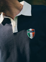 A person wears the BGclubhouse Rugby Sweatshirt - Navy by Blue de Gênes, featuring a white collar, buttons, a crest patch with Italian flag colors, and MMXXVI embroidery on the chest. Part of the Clubhouse Champs Collection.