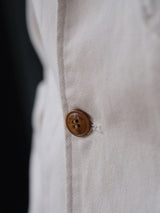 Close-up of the BGbaio Twill Blazer - Chalk by Blue de Gênes, showing its beige cotton twill fabric, brown engraved four-hole button, detailed stitching, and classic regular fit.