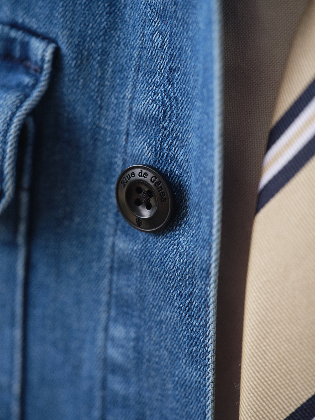 Close-up of the BGpontus Denim Overshirt - Used by Blue de Gênes in blue cotton blend with a black button engraved 