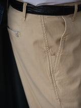 Close-up of a person wearing Blue de Gênes BGpalco Rodas Pants in pale khaki—a relaxed regular fit chino with front pocket and black belt, styled effortlessly with a tucked-in white shirt.