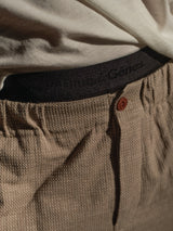 A close-up shows a person in beige textured pants and a white shirt, revealing the waistband of Blue de Gênes BdG Boxershorts - 3 Pack - Black underneath.