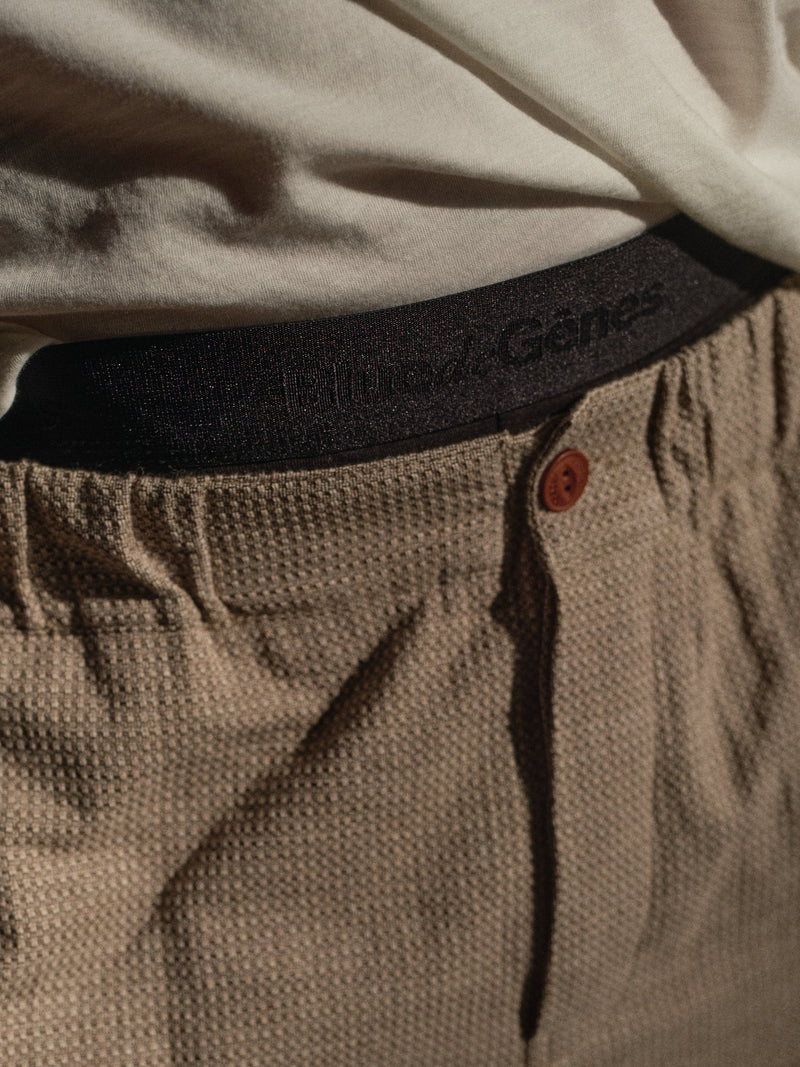 A close-up shows a person in beige textured pants and a white shirt, revealing the waistband of Blue de Gênes BdG Boxershorts - 3 Pack - Black underneath.