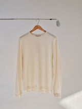 The Blue de Gênes BGmonty Knit - Chalk, a cream-colored long-sleeve cotton-linen blend shirt, hangs on a wooden hanger suspended from a golf club against a plain, light background.