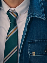 A person wearing the BGponsy Tie - Green by Blue de Gênes and a white button-down shirt under a blue denim jacket, shown from the chest up.