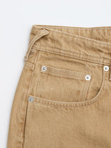 Close-up of the front pocket area of Blue de Gênes BGgiacomo Color Jeans - Tanin, showcasing stitching details, rivets, and part of the waistband in tan rigid denim against a white background.
