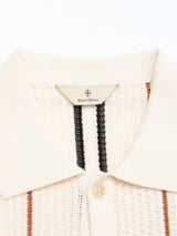 Close-up of the BGwalter S/S Cardigan in Chalk by Blue de Gênes, a cream-colored 100% cotton knit shirt with a collar, buttons, and textured vertical black and brown stripes.
