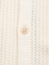 Close-up of the BGwalter S/S Cardigan in Chalk by Blue de Gênes, showing its cream-colored waffle-textured fabric and a round beige button—part of this stylish short sleeve knit cardigan.