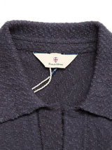Close-up of the BGjohn Slubby Polo in Dark Navy by Blue de Gênes, showing its textured John collar and a tag featuring the brand name with a small shield emblem, evoking classic vintage leisurewear style.