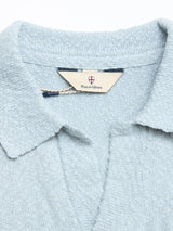 Close-up of the BGjohn Slubby Polo in Blue Fog by Blue de Gênes. Features a textured knit, John collar, V-neck, and an inner tag with the Blue de Gênes name and shield logo for classic vintage style.