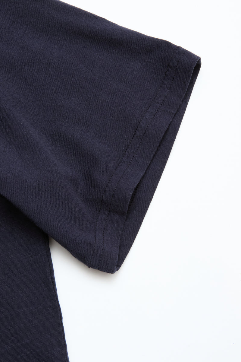 Close-up of the short sleeve and shoulder of a BGoscar T-Shirt - Dark Navy by Blue de Gênes, showing its classic crewneck design, laid flat on a white surface.