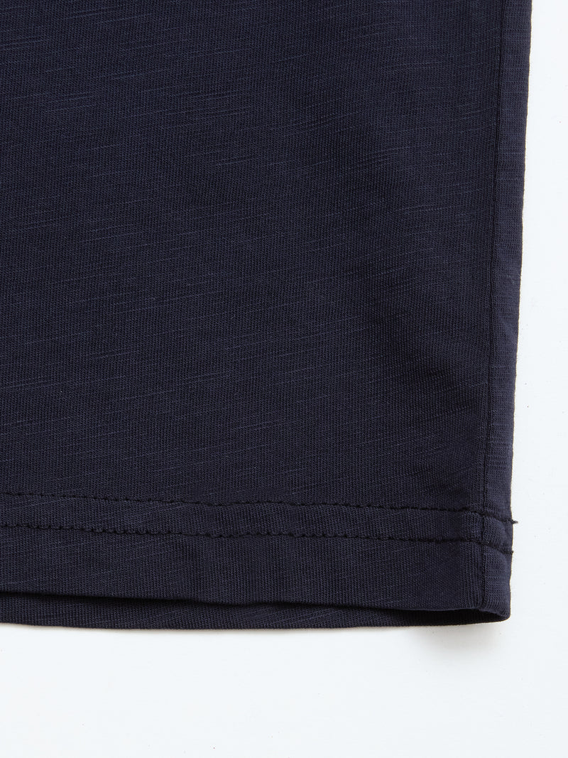 Close-up of the hem on a Blue de Gênes BGoscar T-Shirt in dark navy 100% cotton, showing parallel stitching near the edge against a white background.