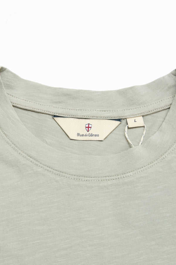 Close-up of the BGoscar T-Shirt in Shadow Green by Blue de Gênes, featuring a crewneck style, inner label with branding and shield logo, size L tag, and soft 100% cotton fabric with a subtle texture.