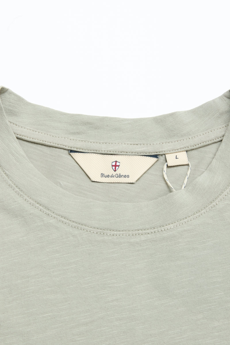 Close-up of the BGoscar T-Shirt in Shadow Green by Blue de Gênes, featuring a crewneck style, inner label with branding and shield logo, size L tag, and soft 100% cotton fabric with a subtle texture.