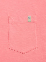 A close-up of the BGoscar T-Shirt in coral by Blue de Gênes, showing the pocket with a small beige tag featuring a black and red shield emblem above it.