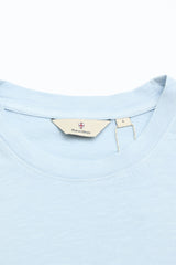 Close-up of a light blue BGoscar T-Shirt - Blue Fog by Blue de Gênes, showing the crewneck collar and beige inner label with brand name and size L, made from 100% cotton, set against a white background.