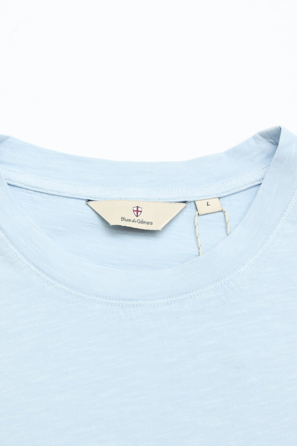 Close-up of a light blue BGoscar T-Shirt - Blue Fog by Blue de Gênes, showing the crewneck collar and beige inner label with brand name and size L, made from 100% cotton, set against a white background.