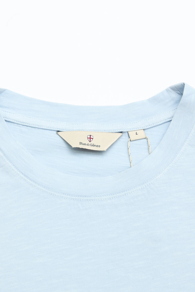 Close-up of a light blue BGoscar T-Shirt - Blue Fog by Blue de Gênes, showing the crewneck collar and beige inner label with brand name and size L, made from 100% cotton, set against a white background.