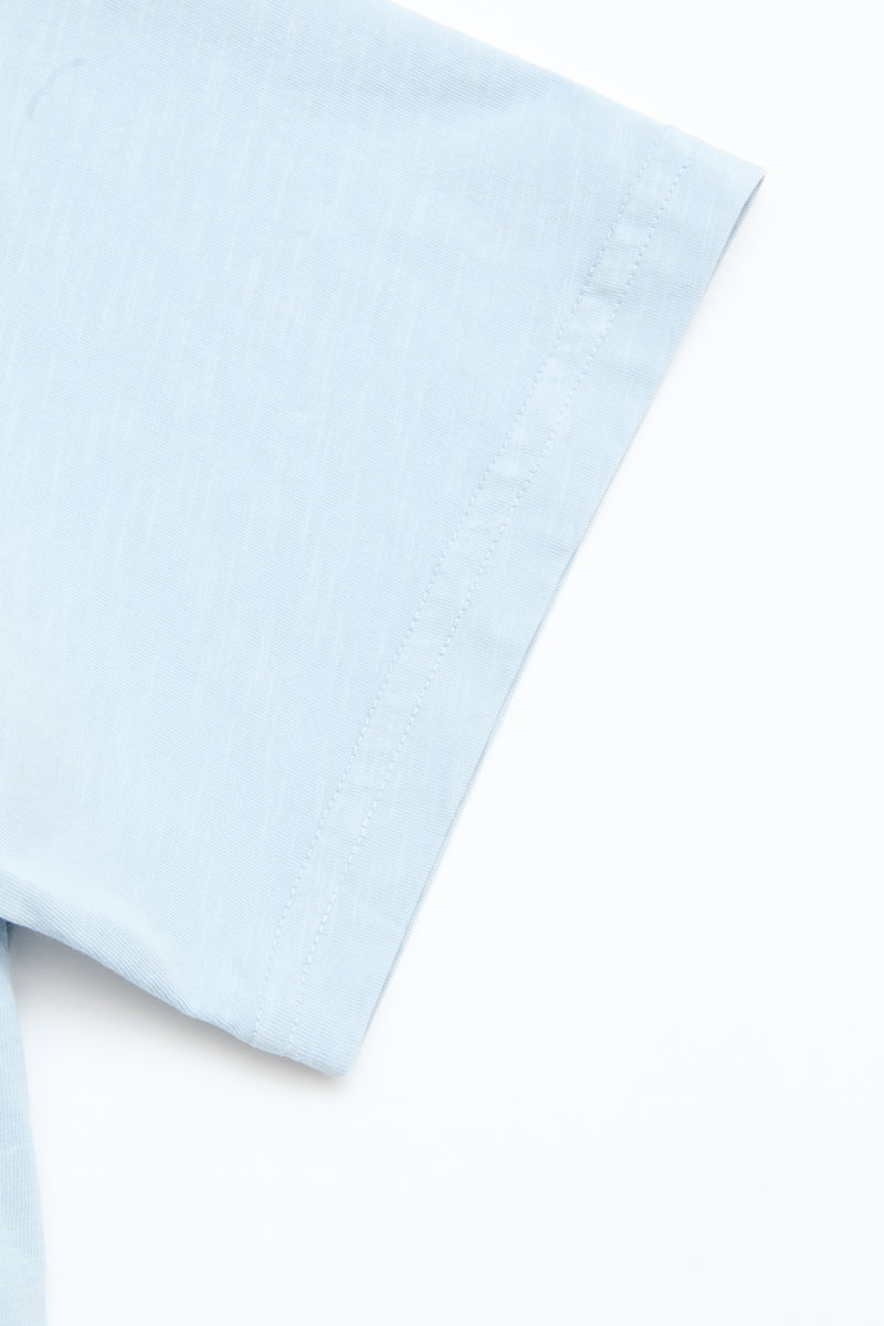 Close-up of the Blue de Gênes BGoscar T-Shirt in Blue Fog, made from 100% cotton, displayed flat on a white surface, highlighting the crewneck, sleeve, and shoulder seam.
